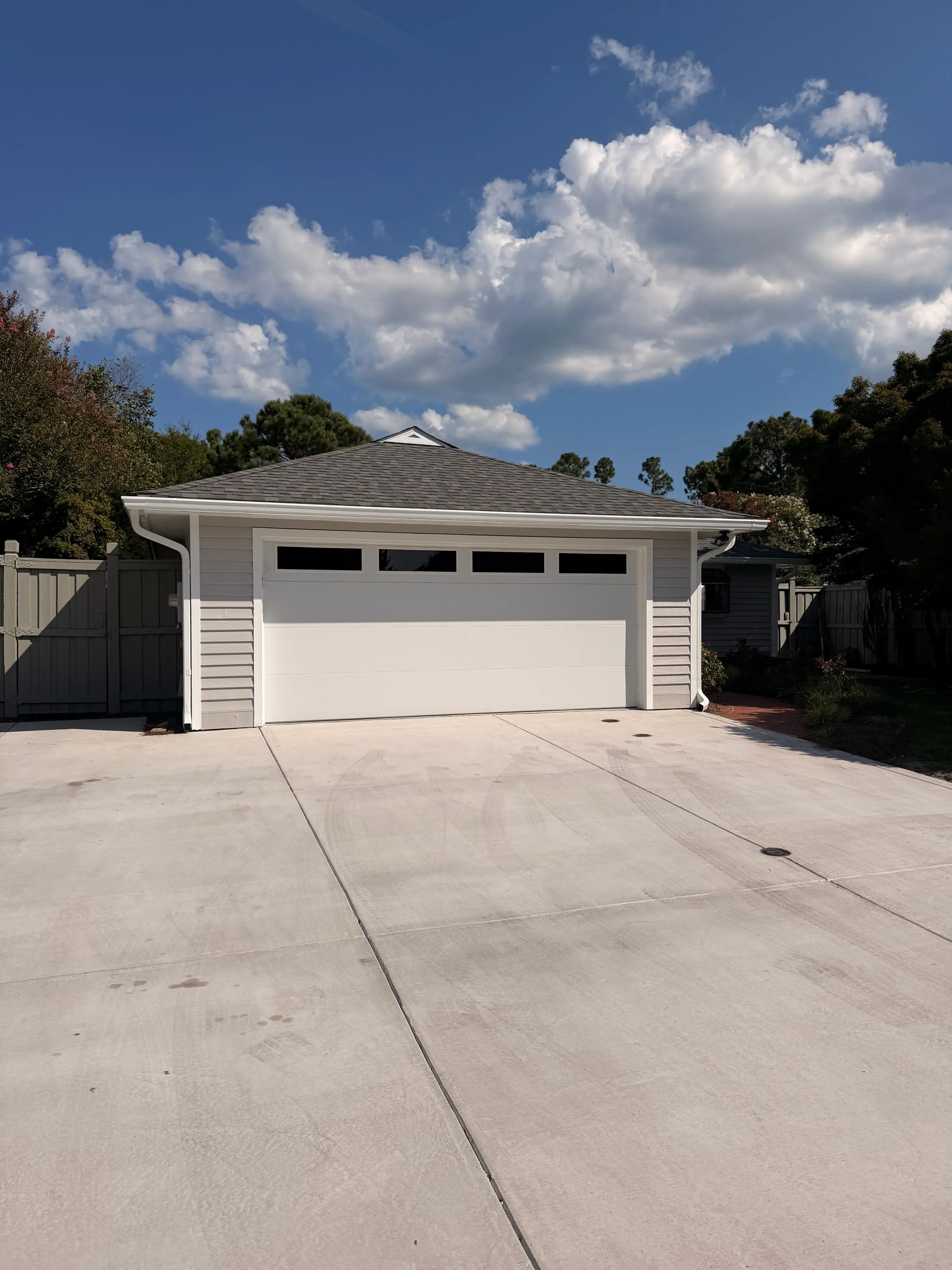White vinyl fence with vertical boards installed along residential property driveway