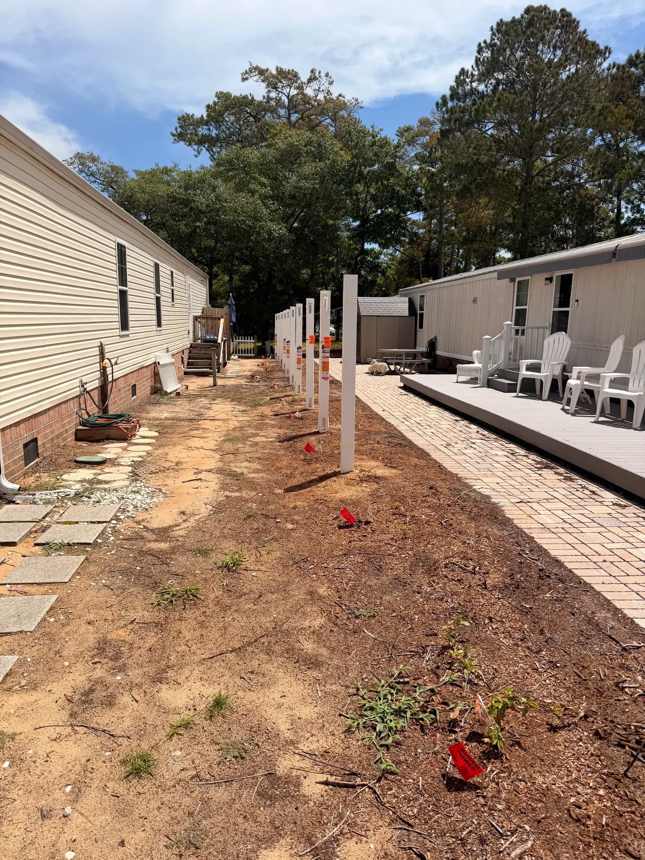 White vinyl fence panels installed along brick residential building with metal posts