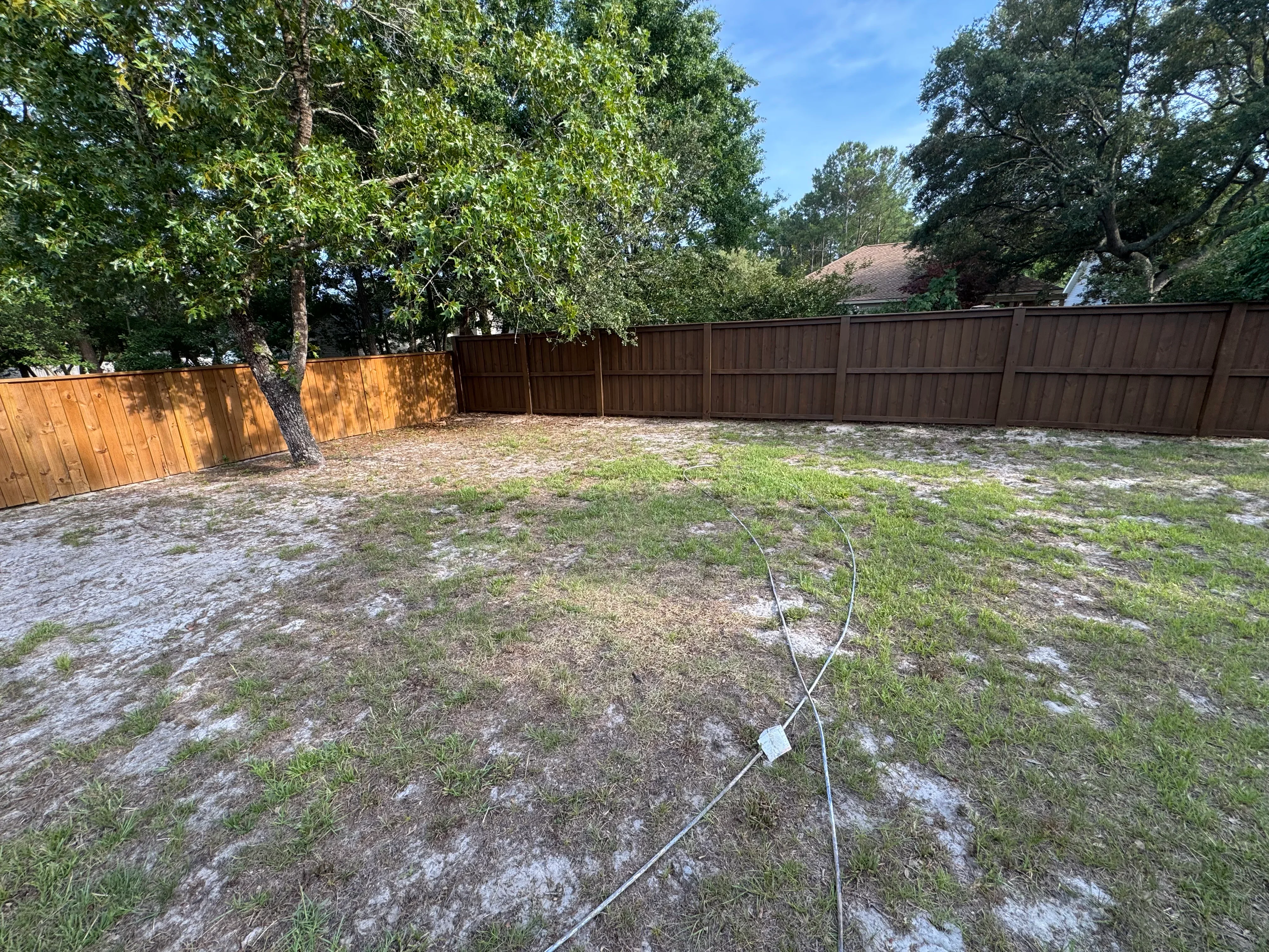 Newly installed wood fence with vertical boards in brown stain, residential backyard