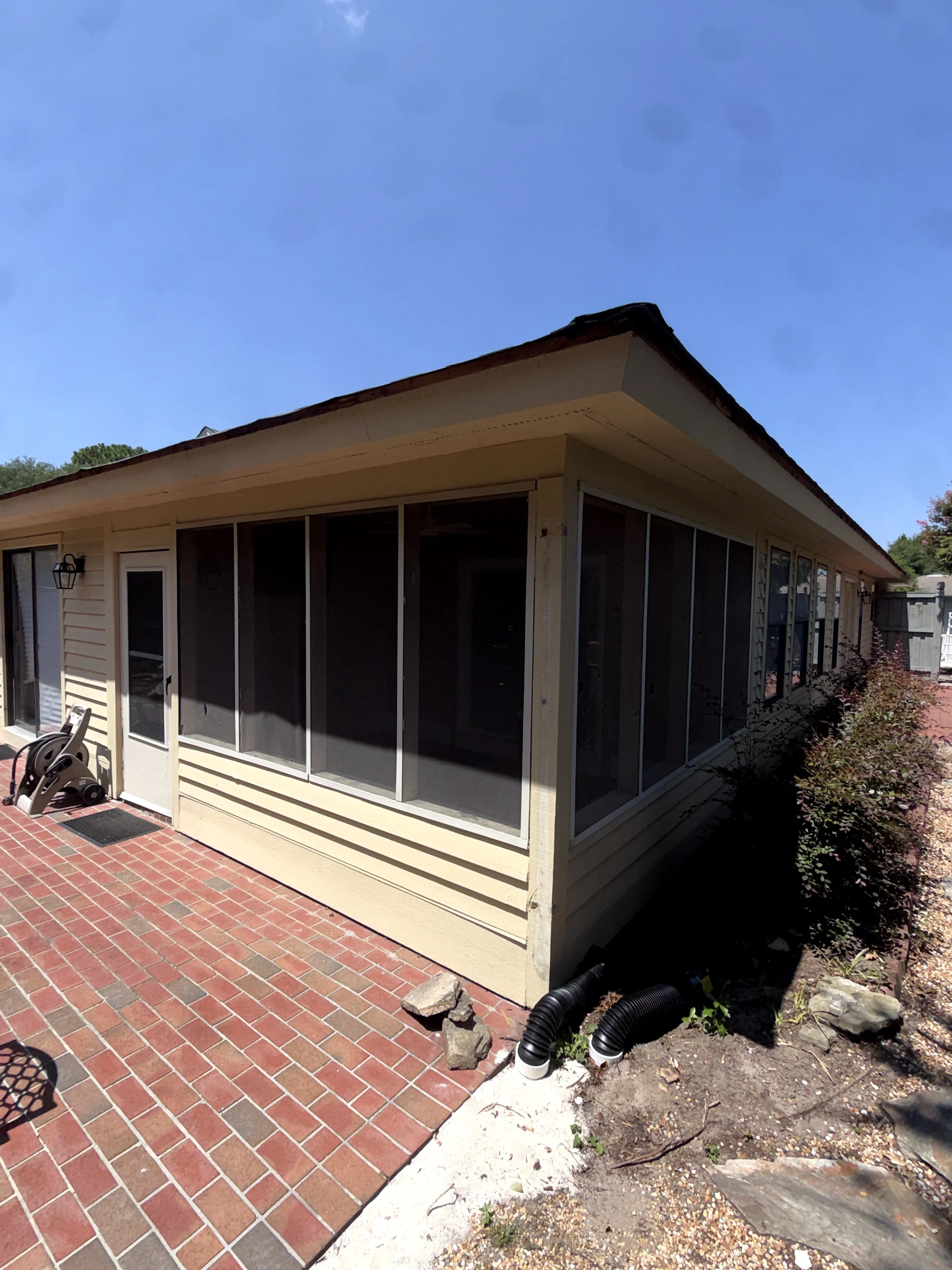 Screened porch with black mesh panels and cream aluminum frame attached to residence
