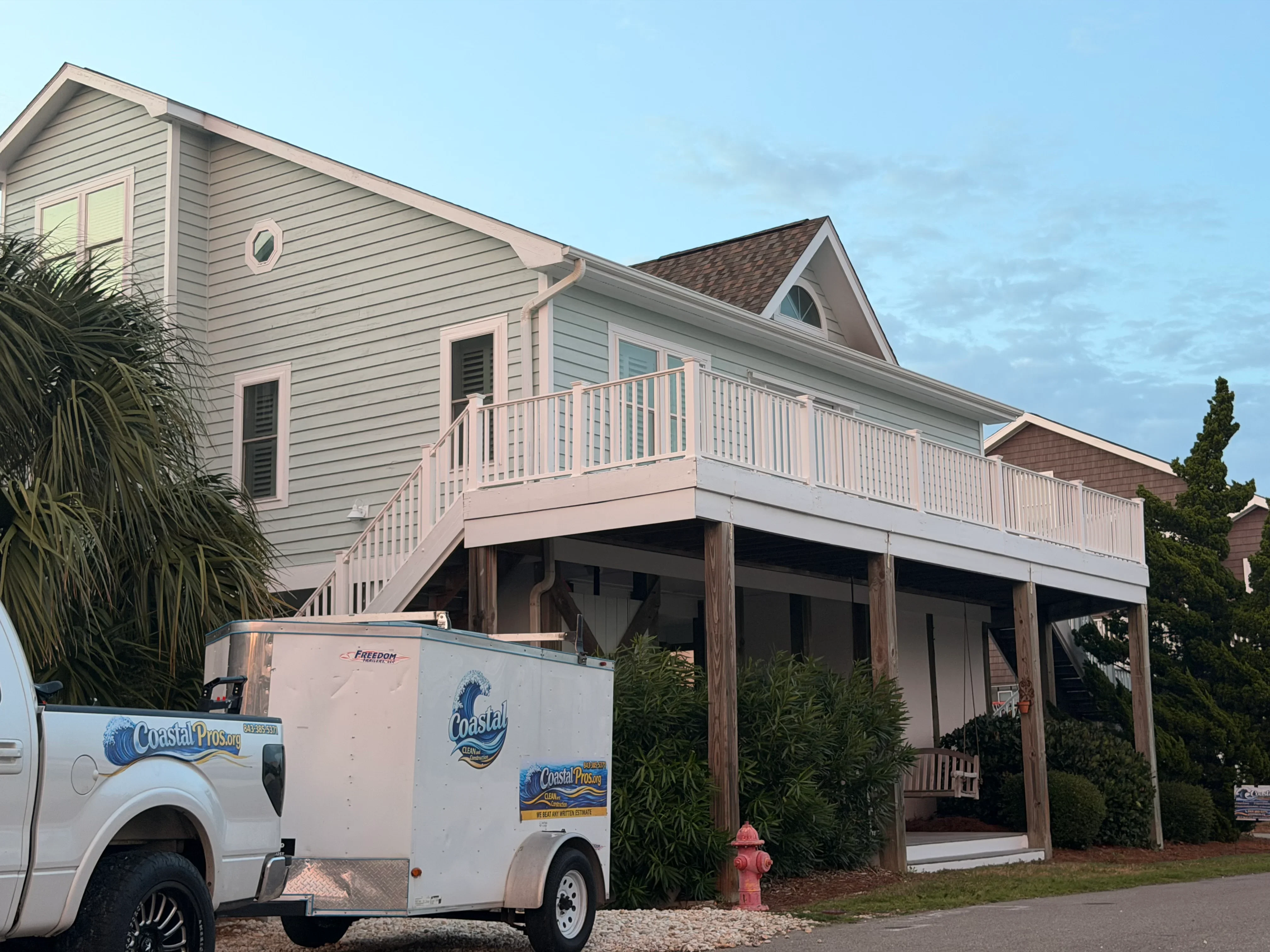 White vinyl deck railing and balusters on elevated wooden deck structure with support posts