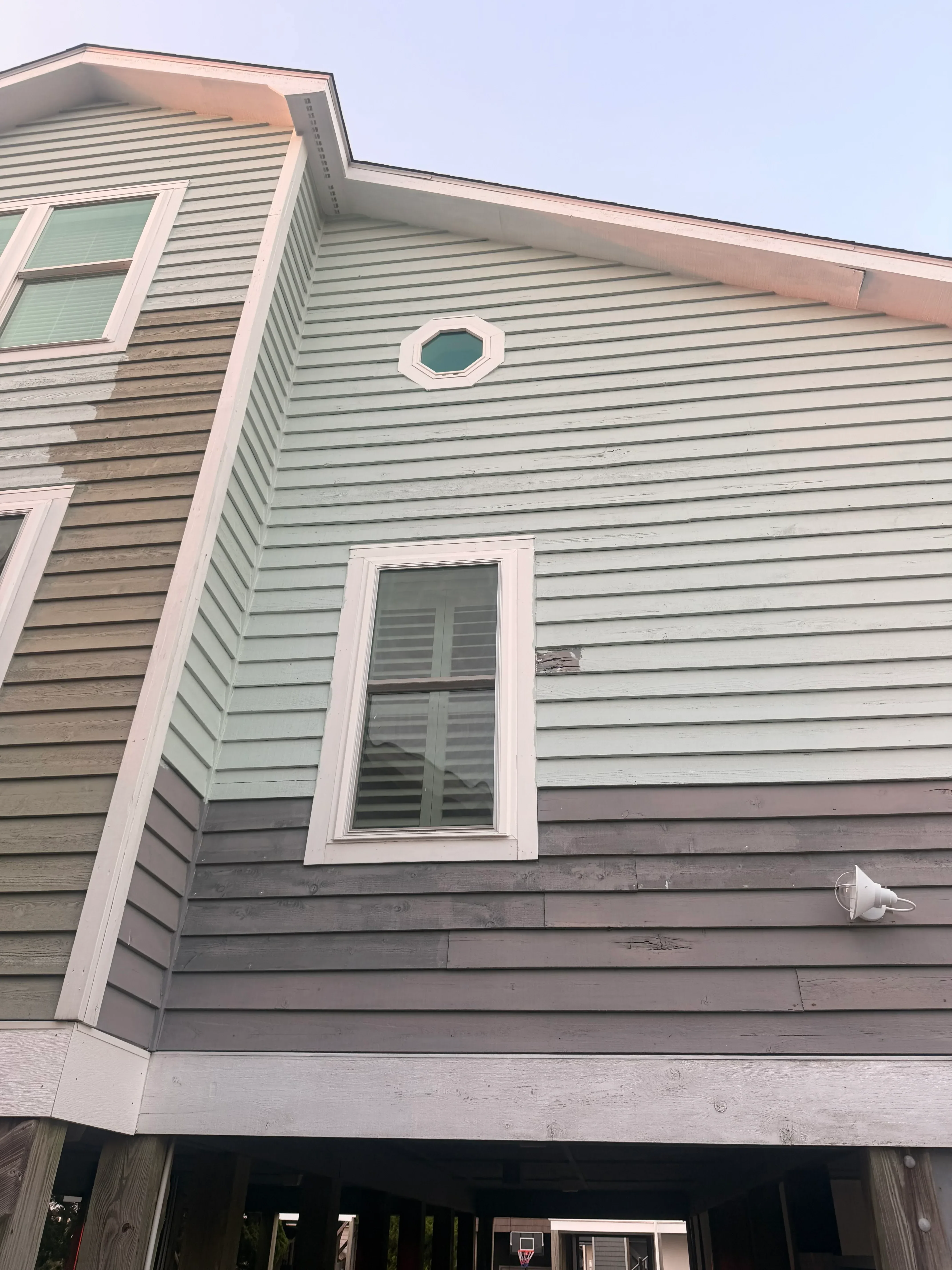 Vertical corrugated metal siding with white-trimmed rectangular window and circular porthole