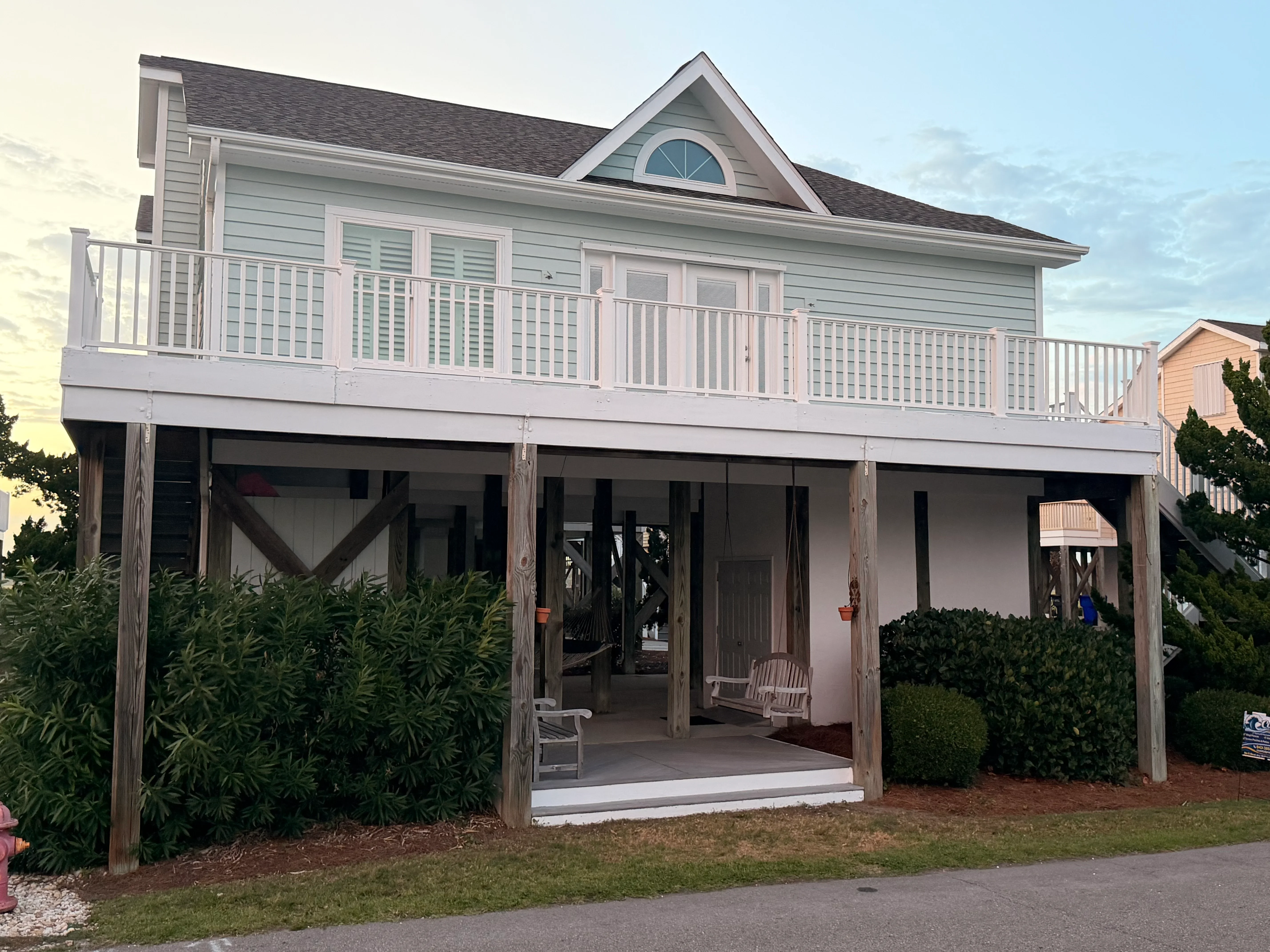 Elevated deck with white vinyl railing, composite decking, and wood support posts