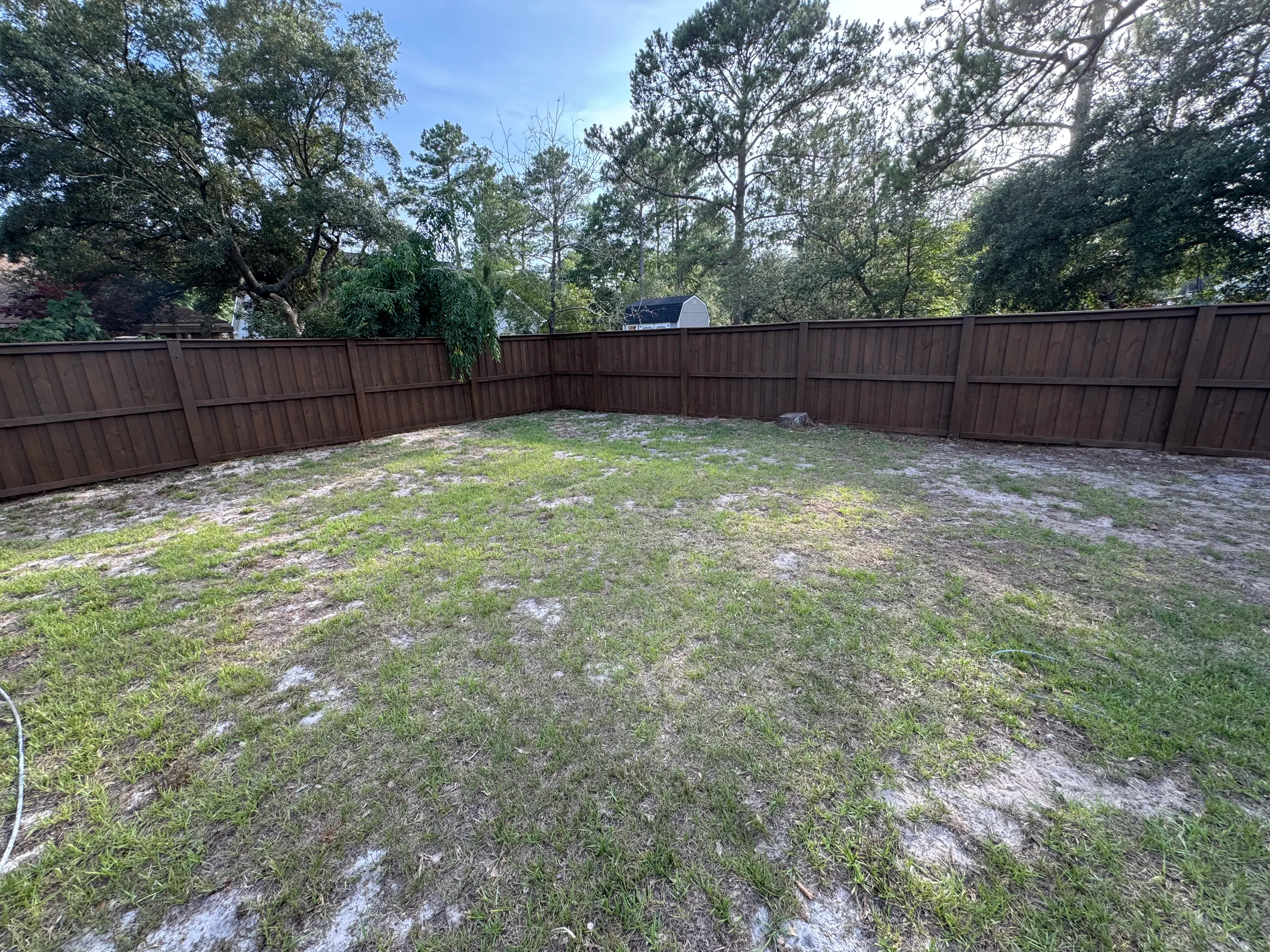 Brown vinyl privacy fence panels installed around residential backyard perimeter
