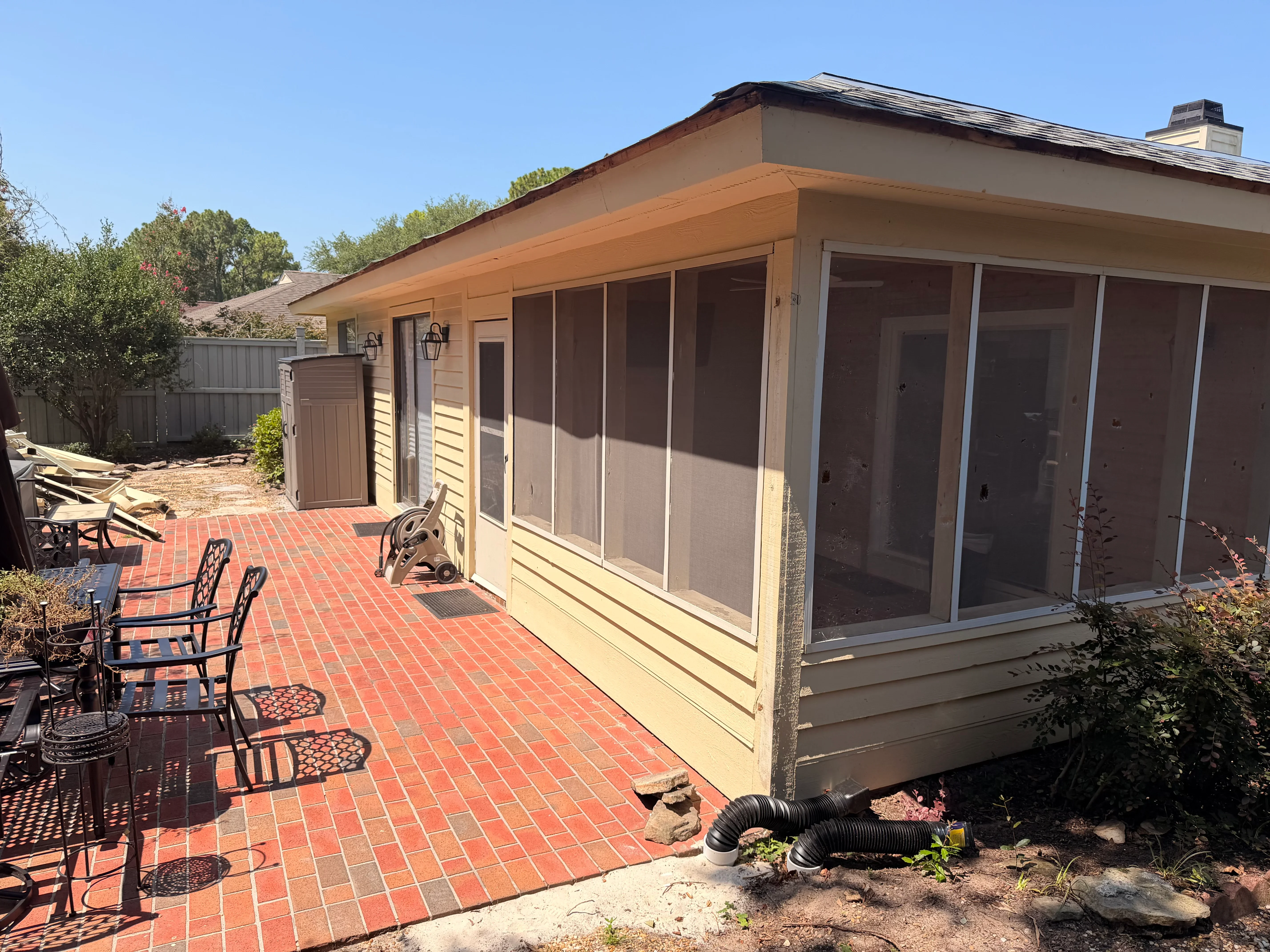 Sunroom with sliding glass doors, cream siding, and red brick patio installation