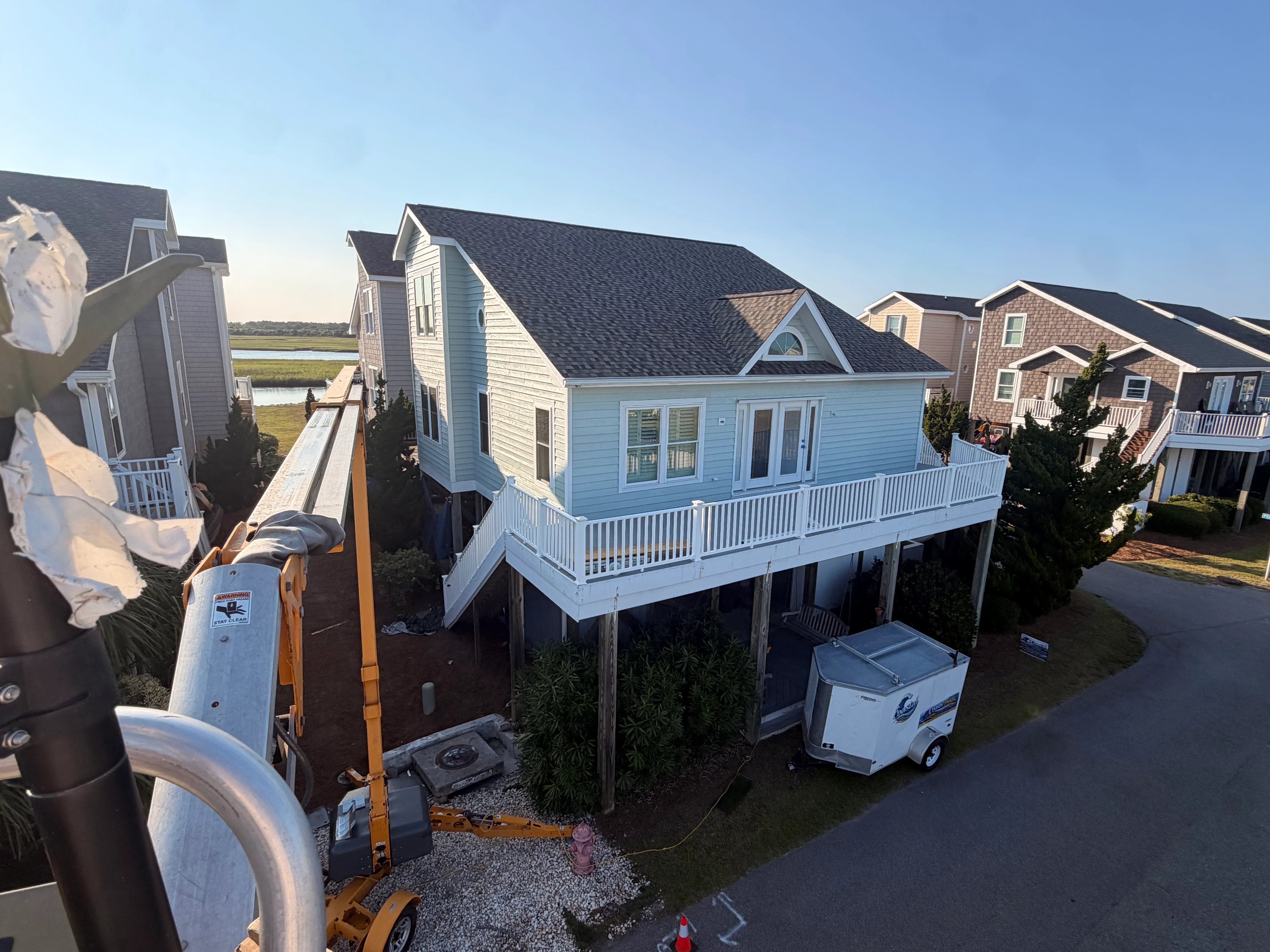 Elevated white vinyl deck with railing on raised coastal home foundation